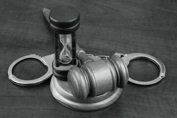 Wooden gavel with handcuffs and hourglass. Time for justice concept.
