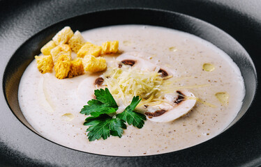 Creamy mushroom soup with champignons on black