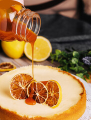 woman pouring caramel on orange cheesecake