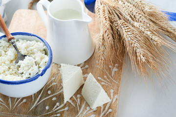 Shavuot jewish holiday celebration. Kosher fresh dairy products milk and cheese, ripe wheat, cream on white wooden background. Dairy products over white wooden background. Shavuot concept. Top view.