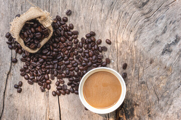 black drip coffee in ceramic cup on old wood table with coffee bean. Barista serve cup of hot black coffee on old wooden table cafe shop in garden with coffee bean.