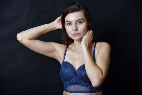 Young woman, brunette. Female model with navy blue underwear and bra. Studio photo with black background.
