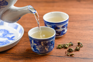 White Ceramic Chinese style Teapot pouring Chinese tea in Ceramic cup. White Ceramic Chinese style Teapot set for tea break time.