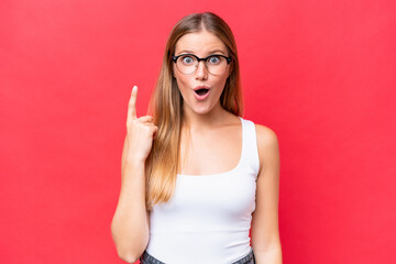 Young beautiful woman isolated on red background intending to realizes the solution while lifting a finger up