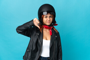 Teenager biker girl isolated on blue background showing thumb down with negative expression