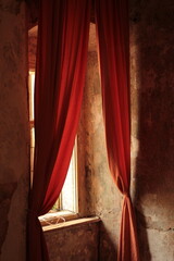 Red curtain behind a window in an old building