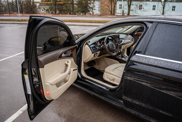 Side view of the open driver's door, mirror, dashboard of the car. Left front door. A new modern shiny parked black car. Interior luxury car with tinted glass standing at parking. Modern car exterior.