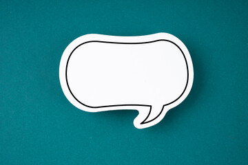 The White speech bubble shaped post it note on green background with copy space.