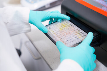Scientific puts microplate into microplate spectrophotometer to analyze multiple samples for...