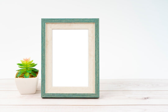The Blank picture frame and plant pot on wooden floor with copy space and clipping path for the inside.