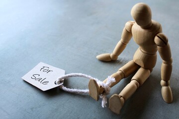 Selective focus image of doll with tag FOR SALE. Human trafficking concept
