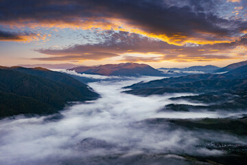 Amazing flowing morning fog in summer mountains. Beautiful sunrise on background. Landscape photography