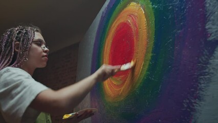 Young female artist paints round picture in small studio