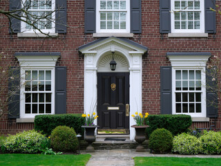 Front door of traditional two story brick house with shutters
