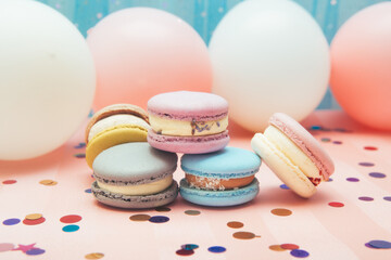 Colorful macaroons cakes on blue and pink background with air balloons, dessert and decoration