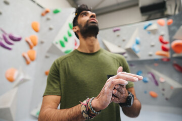 Close Up Of Man Rubbing Hands With Chalk Waiting To Try Climbing Wall At Indoor Centre