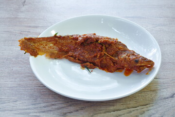 spicy fried Sheatfishes fish topping curry sauce on plate 