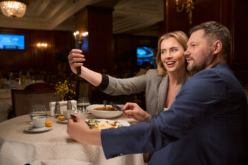 Couple in love taking selfie during dinner at restaurant