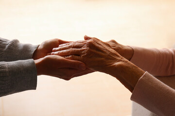 Cropped studio shot of elderly woman and female geriatric social worker holding hands. Women of...