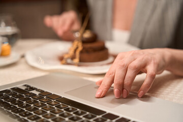Business woman working on laptop during sweet breakfast