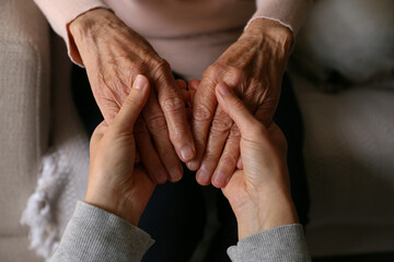 Cropped shot of elderly woman and female geriatric social worker holding hands. Women of different age comforting each other. Close up, background, copy space. - obrazy, fototapety, plakaty