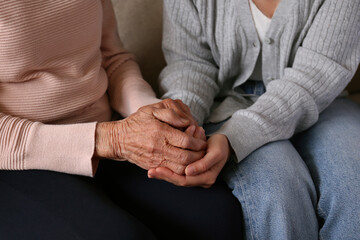 Cropped shot of elderly woman and female geriatric social worker holding hands. Women of different...