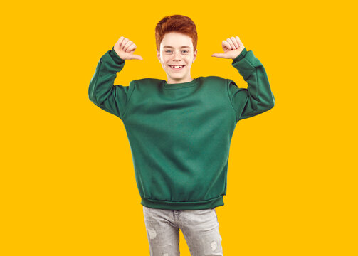 I am the best. Achieved it myself. Happy proud satisfied self assured male child youth model leader boy in modern mockup shirt points thumbs at himself and looks at camera on yellow studio background