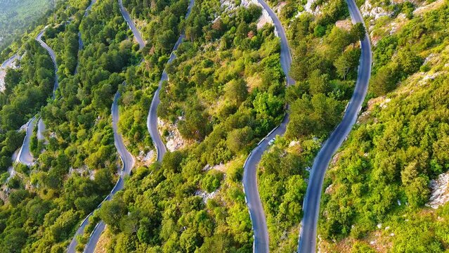 Winding road - Lovcensky serpentine with dangerous turns that leads to the top of the Montenegrin mountains covered with vegetation