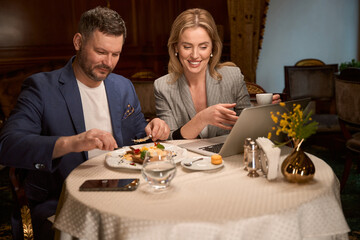 Couple surfing internet on laptop during breakfast in lobby-bar