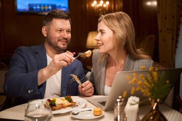 Man treating his girlfriend with tasty dish on date at restaurant