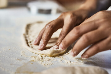 Hands knead dough to make a pizza