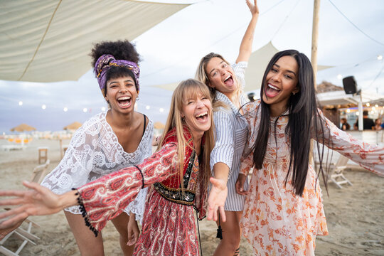 Smiling multiracial girls dancing at sunset beach party - four young girls having fun at  bar