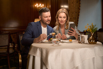 Bride showing variants of hall decoration to groom during lunch