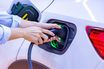 Woman holding the CCS 2 EV charging connector at EV charging station in department store....