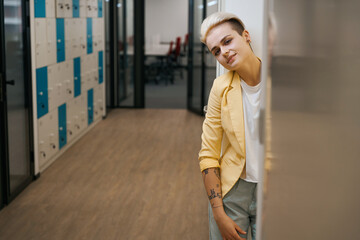 Woman leaning on wall in corridor of coworking office