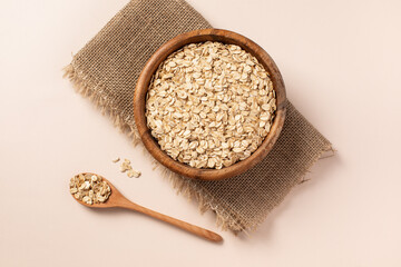 raw oatmeal in a wooden bowl, wooden spoon, light background.
