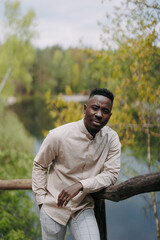 Young african man stands on wooden bridge during outing.