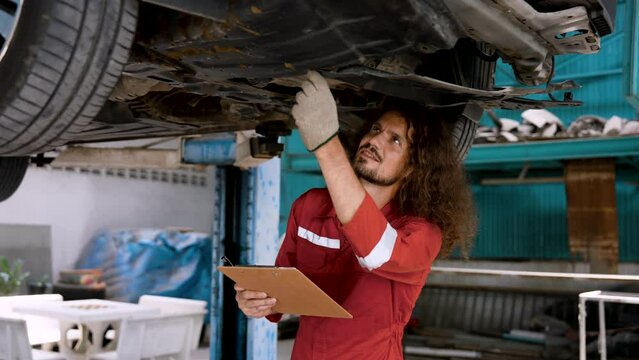 Man car mechanic Caucasian, was inspecting condition car that came into garage with some abnormal car symptoms, keep checkbook on vehicle before repairing it for quick fixes spotting any malfunctions.