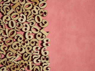 wooden numbers are randomly arranged on pink suede. High quality photo