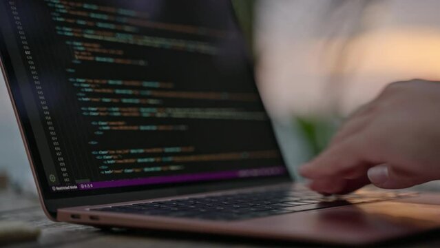 Young female developer working on laptop by the ocean at sunset. Woman freelancer coding at outdoor tropical cafe. Caucasian girl working remotely typing on computer at exotic location close-up