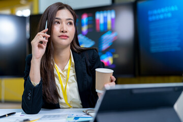 Very stressed business woman and female employee sitting in front of her computer with her hands in front of her eyes, feeling sad and depressed. Too much work - huge pile of paperwork at office table