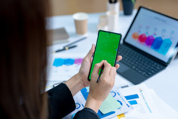 Young business woman on the phone at the office.Business woman texting on the phone and working on laptop.Beautiful young business woman sitting in office.Business woman smiling.