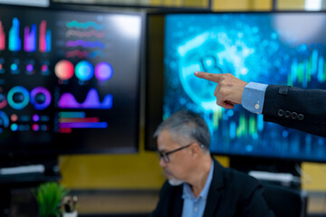 left hand and forearm of a businessman with black suit jacket sleeve with blue shirt, pointing projection screen in the meeting room looking at screen analyzing invest strategy, financial risks.