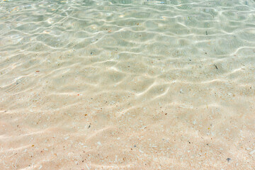 clear turquoise shallow water on white yellow tropical sand beach. Tropical background of paradise water with light reflections.