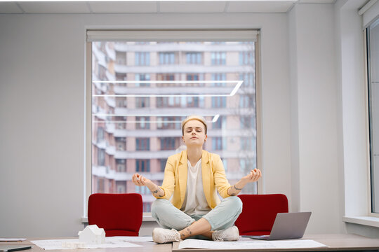 Woman meditating sitting in lotus asana on work desk