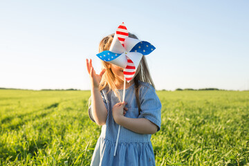 US Independence Day. patriotic background with kids. child girl with pinwheel in field in nature in summer outdoor. kids fun