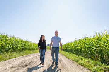 Couple of farmers entrepreneurs walking in a field of corn 