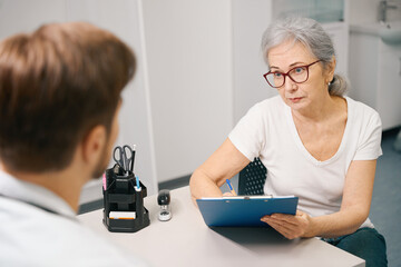 Elderly patient fills out a medical form at doctors appointment
