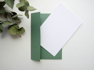 Greeting, post card, invitation white card photo mock up with green envelope on the white background with the eucalyptus.
