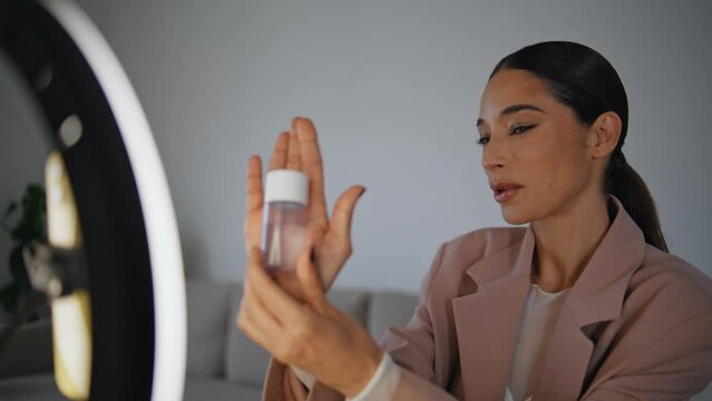 Talking blogger showing cosmetic to mobile phone closeup. woman filming tutorial